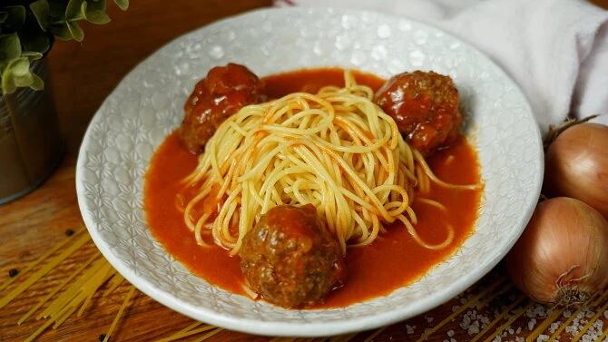 Pasta s masovými kuličkami v rajčatové omáčce na talíři.