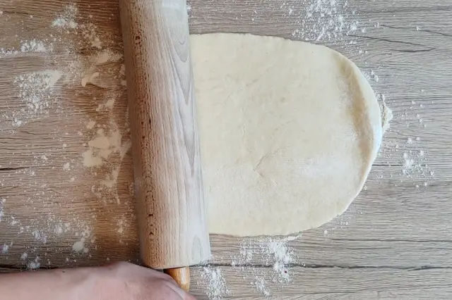 Rozkvedání těsta válečkem na stolu pro štrúdl nebo závin.