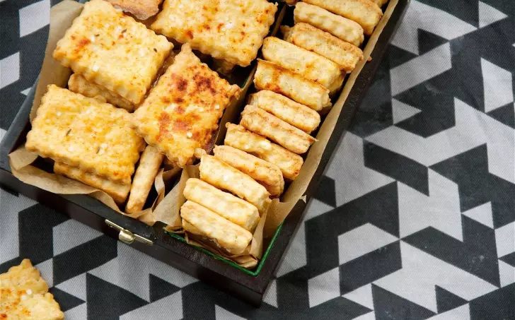 Tray plný slaných sýrových sušenek v dřevěném podnosu.