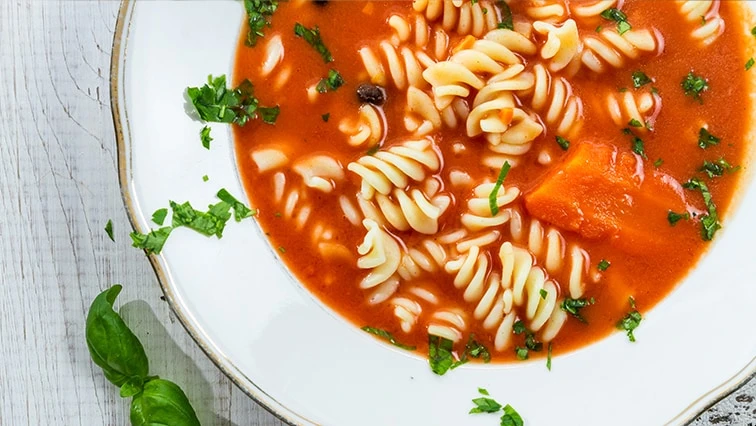 Červená italská polévka s těstovinami fusilli a čerstvou petrželkou.