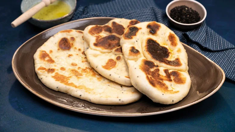 Tři kousky indického chleba naan podávané na talíři.
