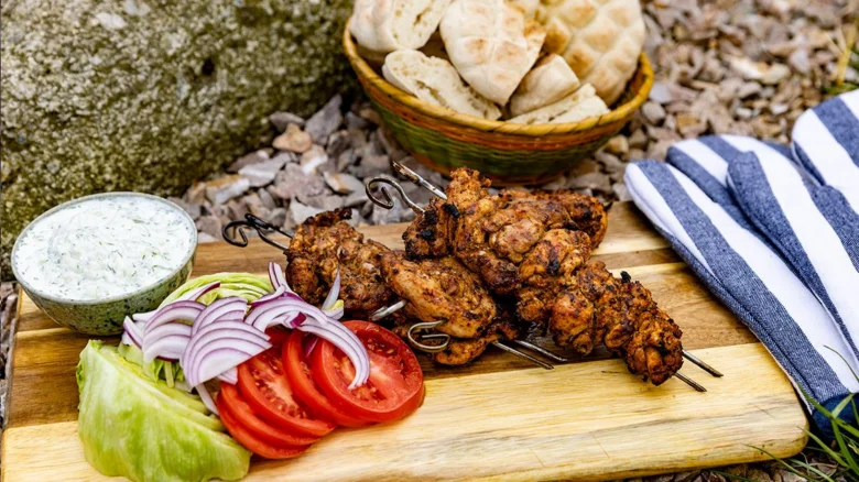 Pečené kuřecí souvlaki s čerstvými zeleninovými přílohami.