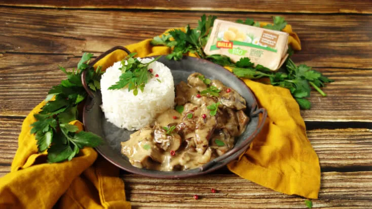 Hovězí stroganoff s rýží a petrželkou na talíři.