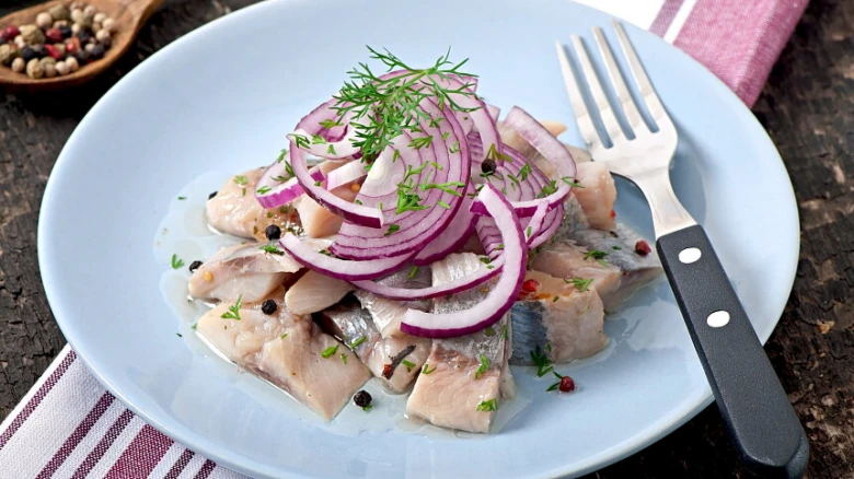 Uzený sardinka se cibulí, koprem na talíři.