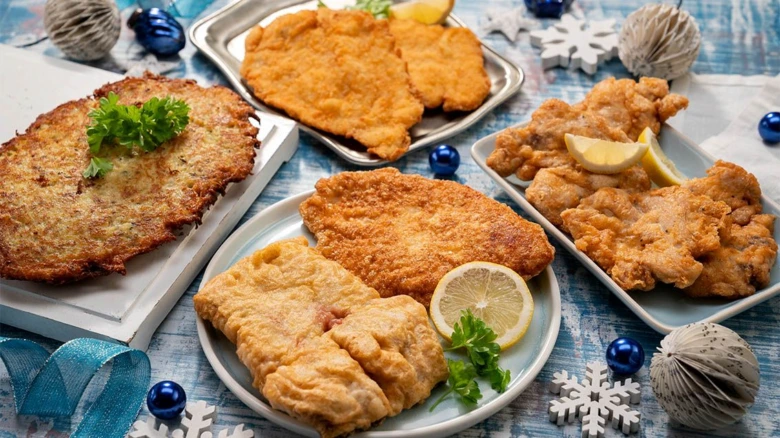 Různé typy obalených řízků s citronem a petrželkou na vánočním stole.
