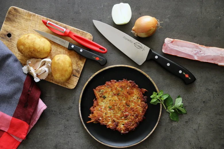 Připravené bramborové placky s surovými ingrediencemi na tmavém povrchu.