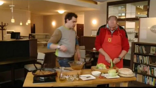 Muži připravují gyros s zeleninou na kuchyňském stole.