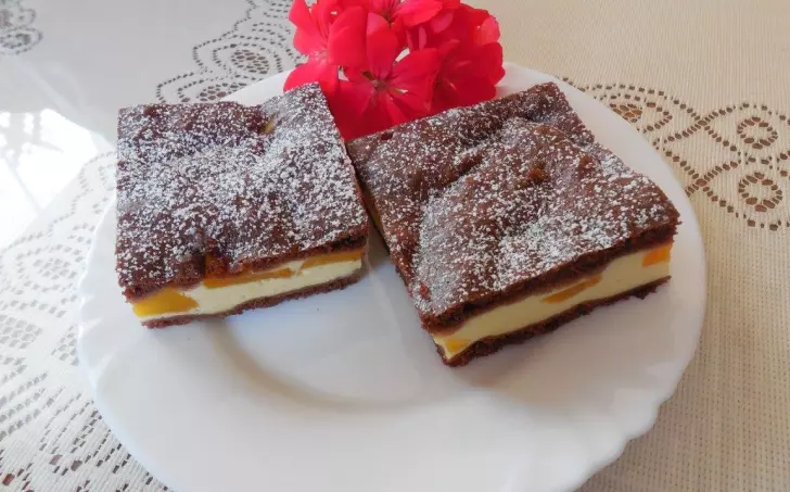 Dva čokoládové řezy s broskví a tvarohem na bílém talíři.
