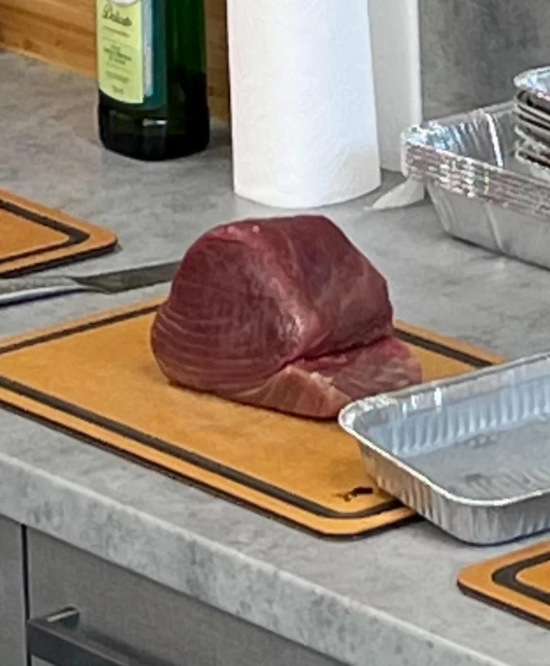 Surový tuňák na řezné desce připravený k vaření.