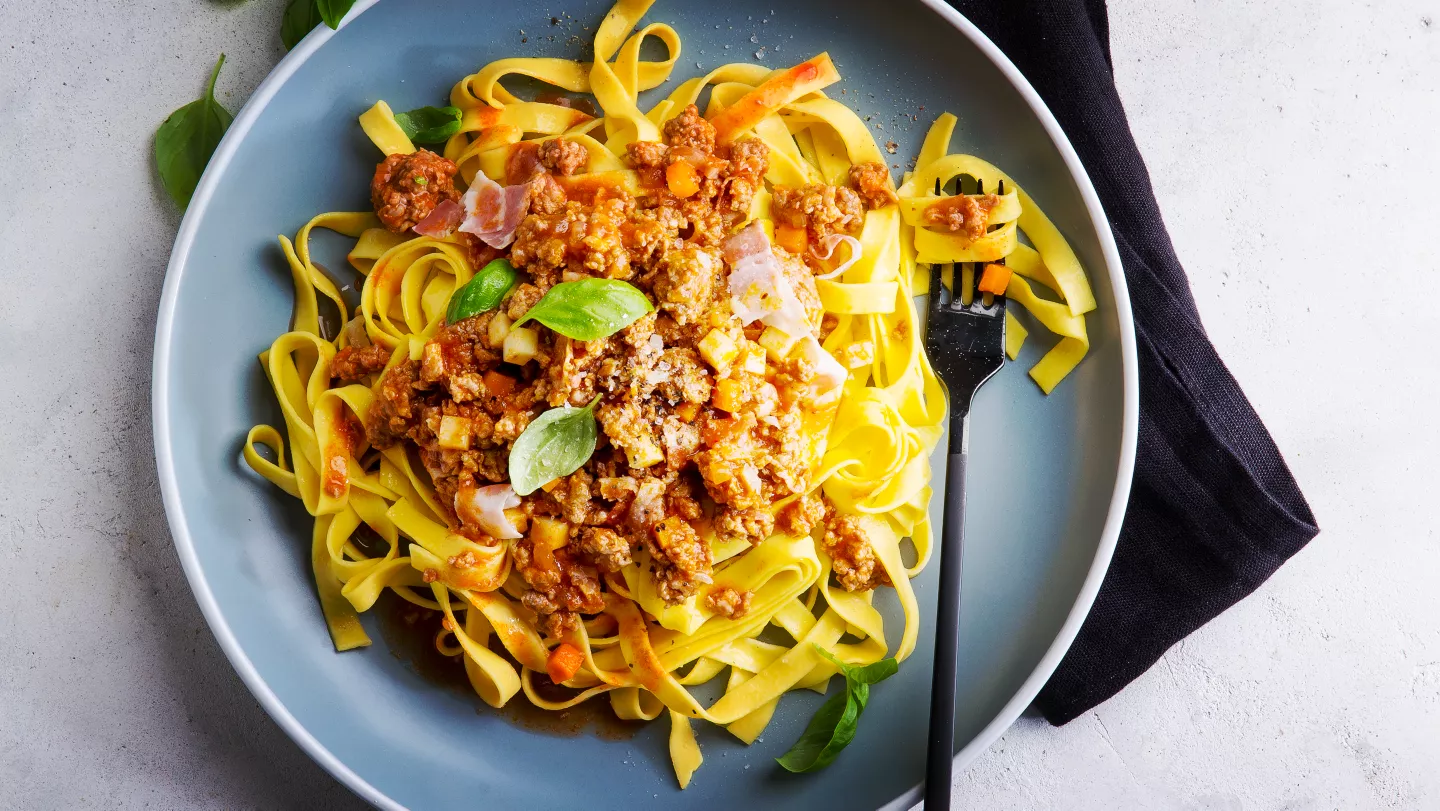 Pasta s boloňskou omáčkou na modrém talíři.