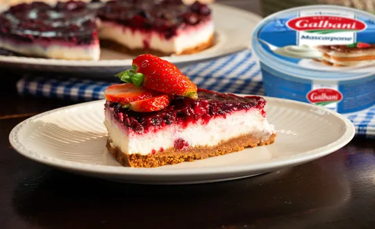 Kousek jahodového cheesecaku s mascarpone na talíři.