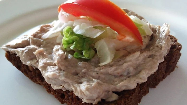Rybičková pomazánka na chlebu s okurkou, cibulí a paprikou.