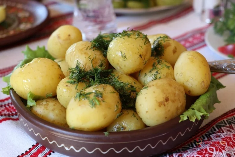 Uvařené nové brambory s koprem v hlinitém misku.