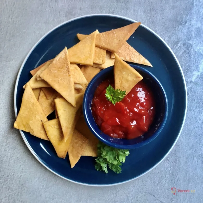 Domácí nachos s čerstvou rajčatovou omáčkou na modrém talíři.