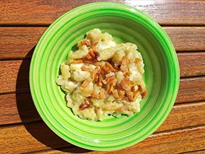 Zelená miska s haluškami, omáčkou a smaženými cibulkami.