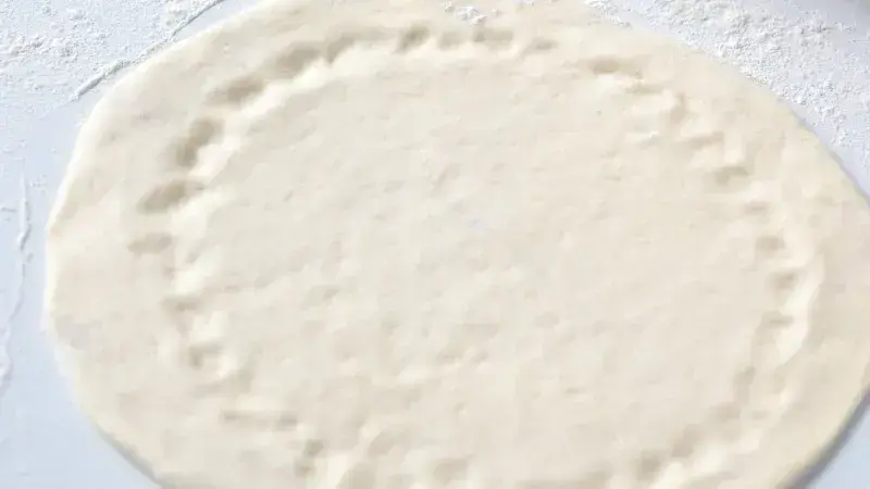 Kroužek těsta na pizzu rozložený před přidáním ingrediencí.