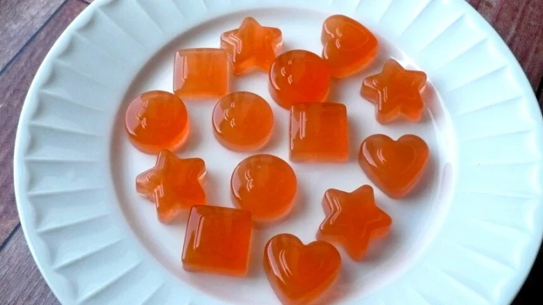Oranžová želé v tvare srdcí a hvězd na bílém talíři.