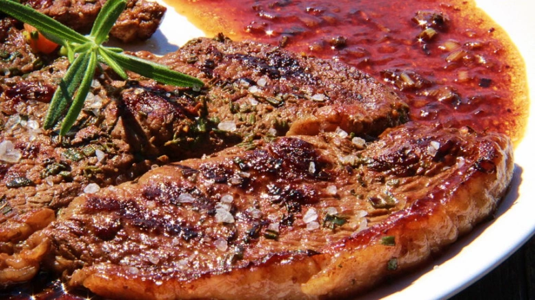 Grilovaný steak s červenou omáčkou a čerstvou rozmarýnou.