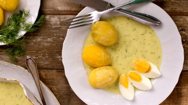 Koprová omáčka s vařenými bramborami a vejci na talíři.