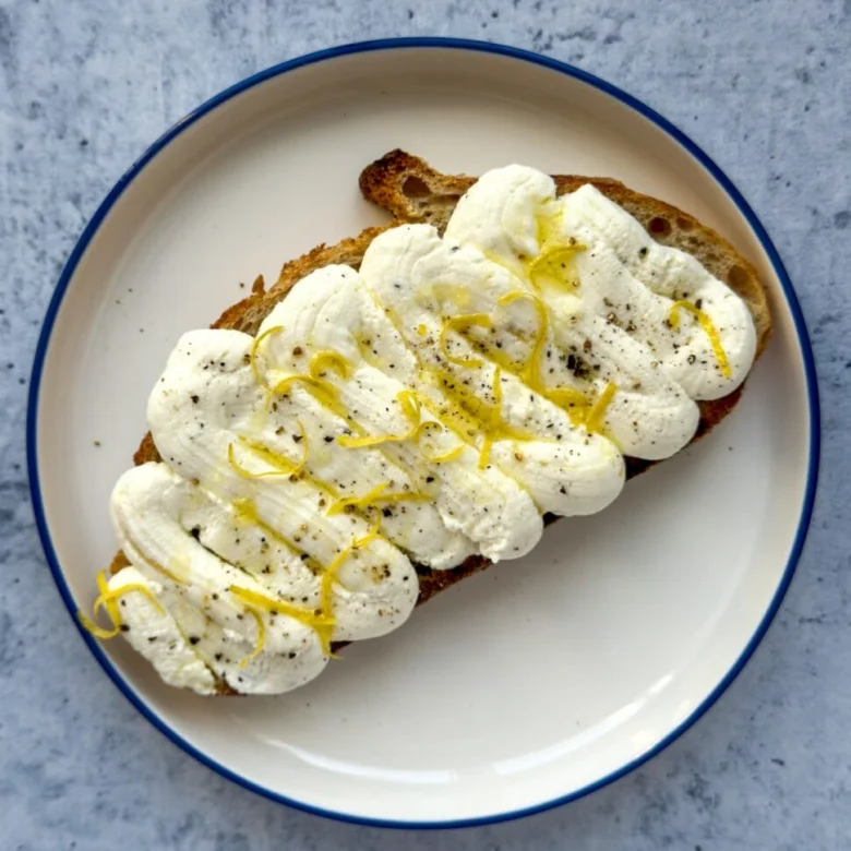 Kousek toastu s ricottou, citronovou kůrou a pepřem.