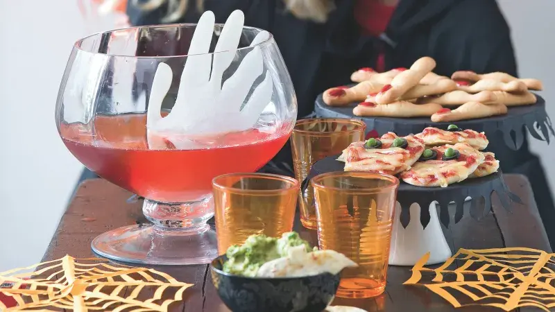 Halloweenské pohoštění pro děti s nápojem v poháru na stole.