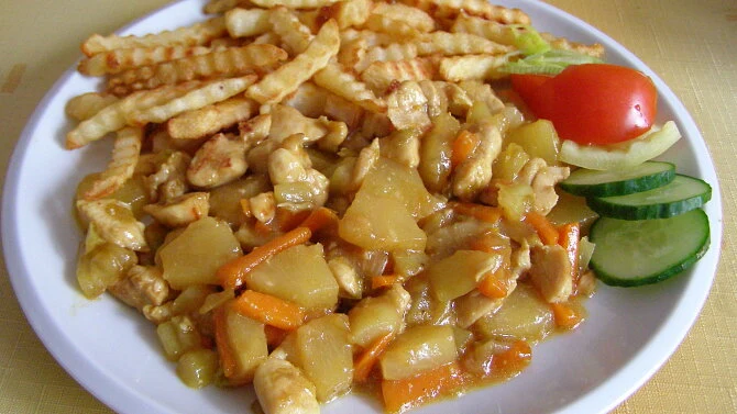 Přepážka kuřecího masa s ananasem a zeleninou na talíři.