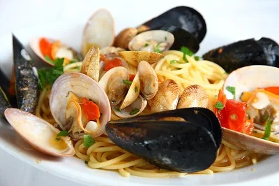 Pasta s mušlemi a krevetkami v bílé misce.