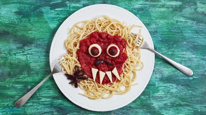 Pasta s tvarem strašidelné tváře na talíři.