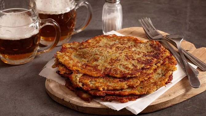 Skládané bramboráky na dřevěném talíři s pivem.