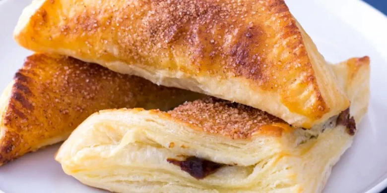 Zlaté listové taštičky s náplní posypané cukrem.