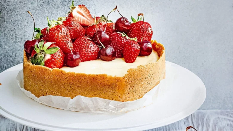 Pečený cheesecake s mascarpone zdobený jahodami a třešněmi.
