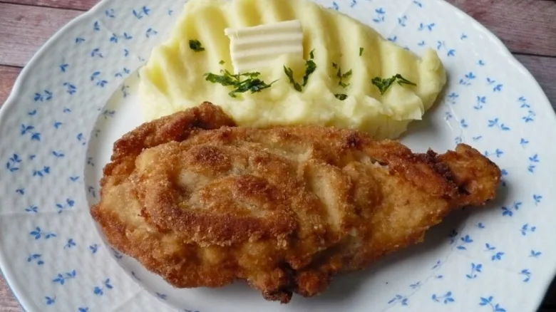 Zlatě opečený řízky s bramborovou kaší na talíři