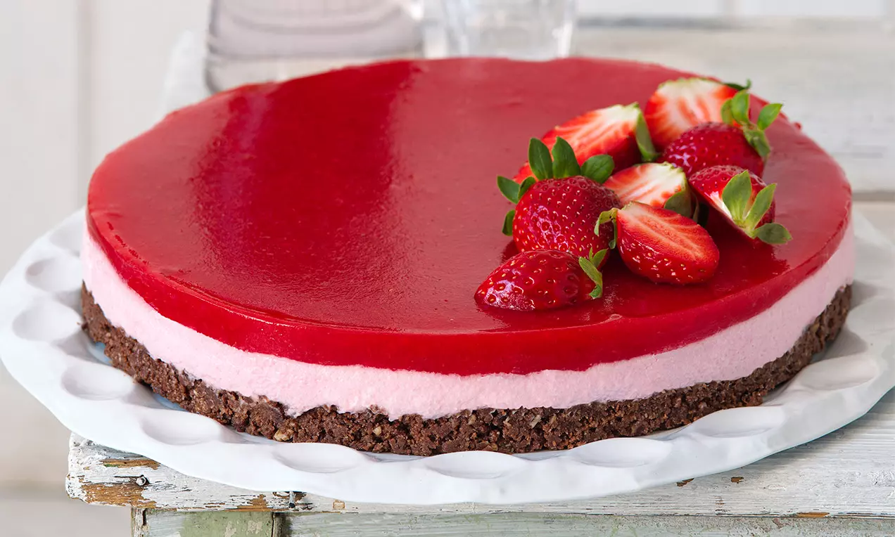 Celý jahodový cheesecake s čokoládovou základnou a malinovým nálevem.
