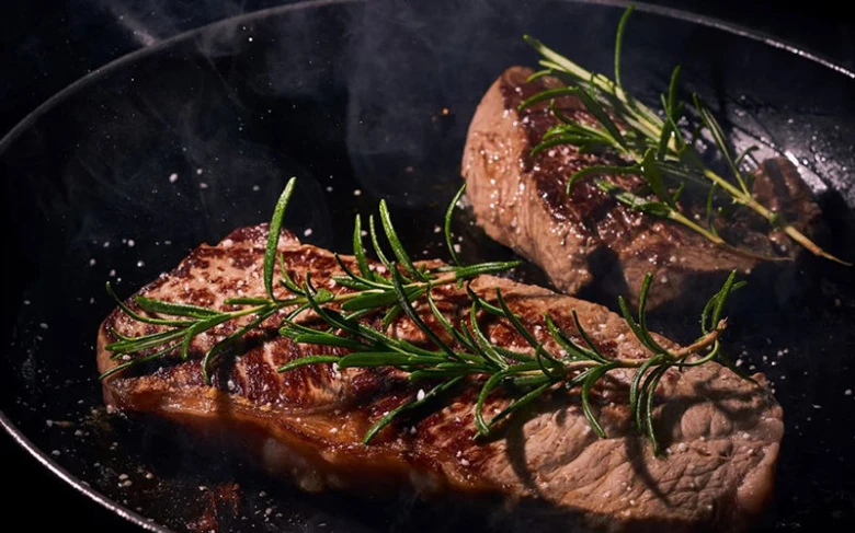 Dva pečené steak na pánvi s rozmarýnem.