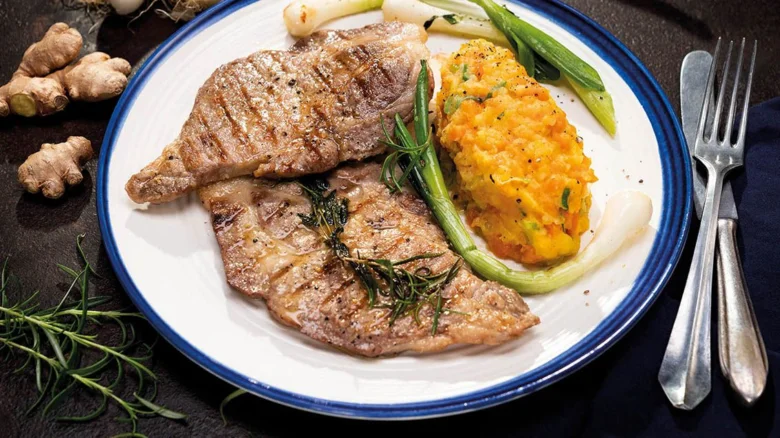 Připravený steak s bramborami a zeleninou na talíři.