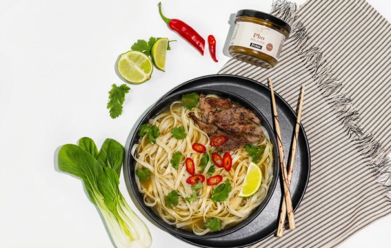 Miska vietnamské polévky pho s nudlemi, masem a zeleninou.
