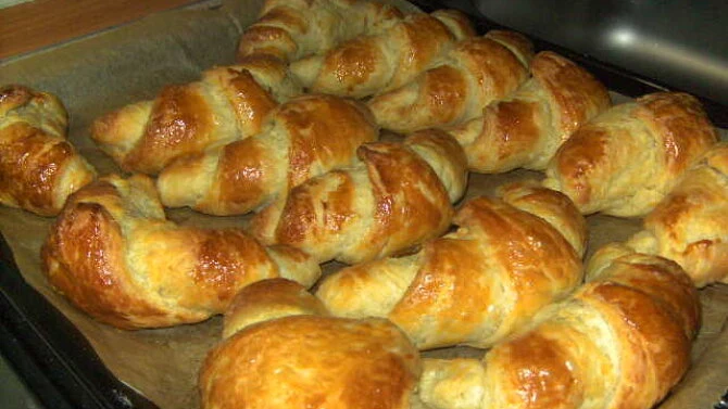 Zlatohnědé domácí croissanty právě vypečené na plechu.