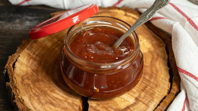 Sklenice domácí omáčky na grilování s lžící uvnitř.