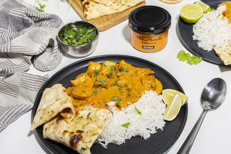 Plov s kuřecím tikka masalou a chlebem na talíři.