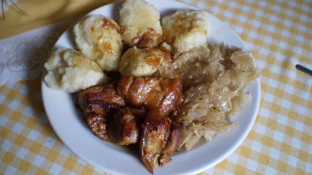 Tradiční české knedlíky s masem a kysaným zelím na talíři.