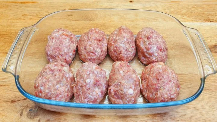 Surové mleté masové kuličky v skleněné pekáči.
