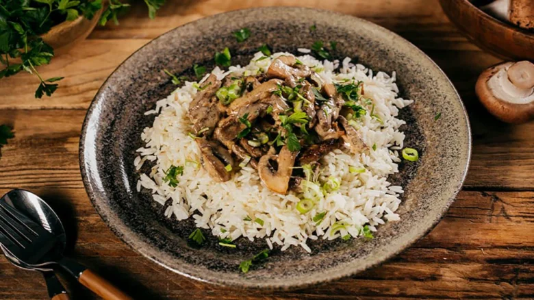 Hovězí stroganoff s rýží, houbami a bylinkami v hrnci.