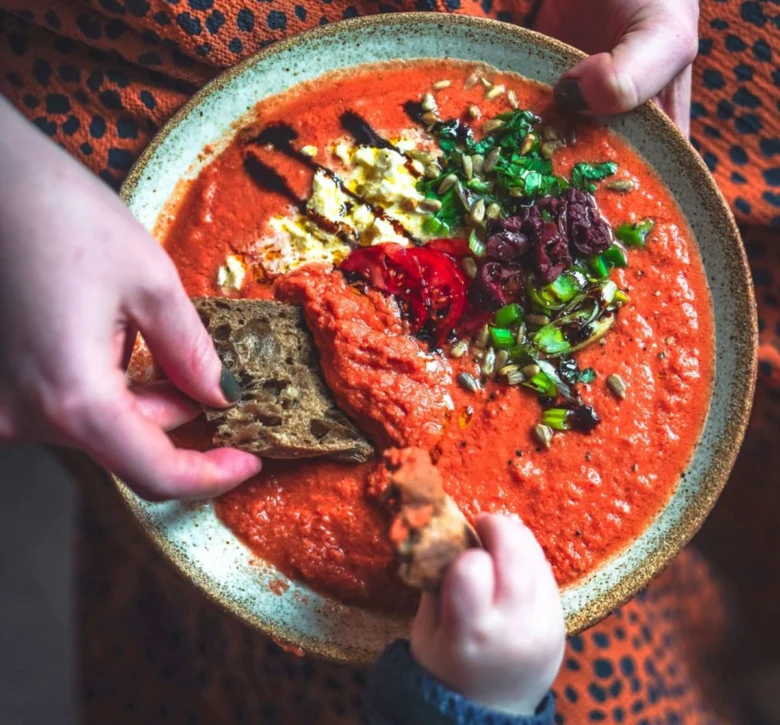Miska s červenou polévkou gazpacho ozdobená zeleninou.