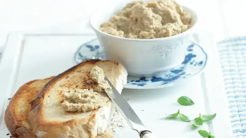 Mísa s hummusem na kouscích toastu s nožem.