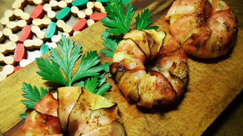 Připravené anglická slanina obalené jídlo na dřevěném prkénku s petrželkou.