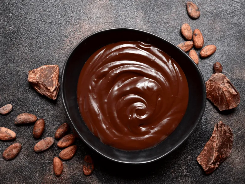 Čokoládová ganache v černé misce s kousky kakaa.