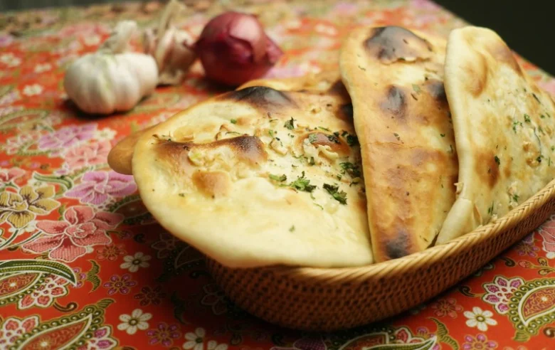 Kos s čerstvými plackami naanem posypaným bylinkami.