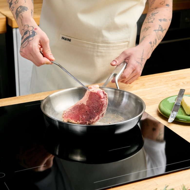 Kuchař položí surový steak na horkou pánvi.