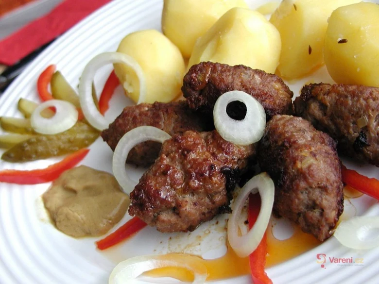 Připravené biftečky z mletého masa s bramborami a cibulí