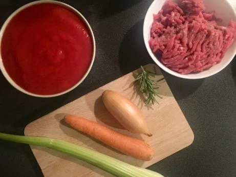 Suroviny pro boloňskou omáčku: maso, rajčatová pasta, cibule, mrkev.
